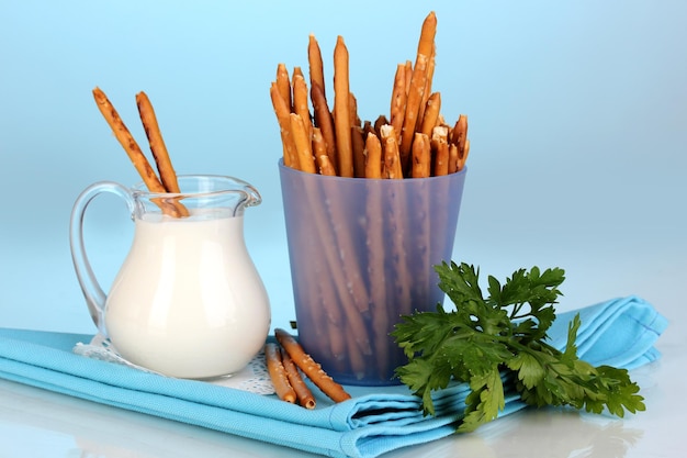 Tasty crispy sticks in purple plastic cup on blue background