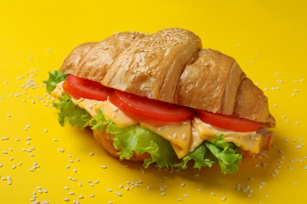 Tasty croissant sandwich on yellow, close up