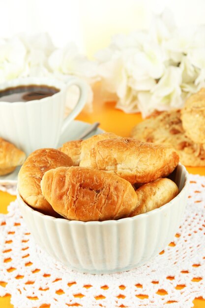 Tasty croissants and cup of coffee on table closeup