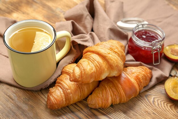 Tasty croissants and mug of tea on wooden table