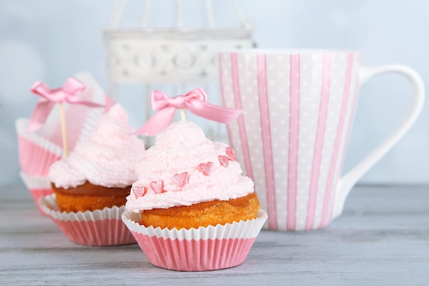 Tasty cup cakes with cream on grey wooden table