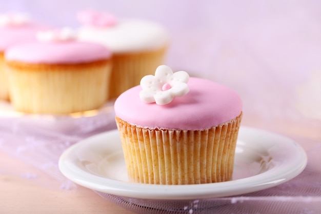 Tasty cupcake on saucer on light background