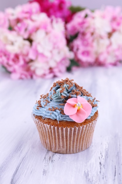 Tasty cupcake with butter cream on color wooden background