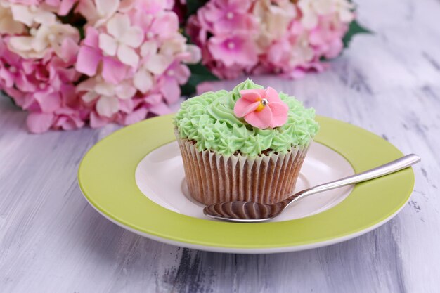 사진 색상 나무 배경에 접시에 버터 크림과 함께 맛있는 컵 케이크