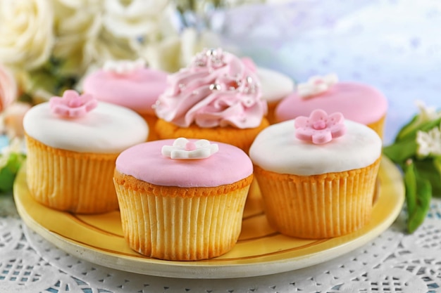 Tasty cupcakes on plate on color wooden background