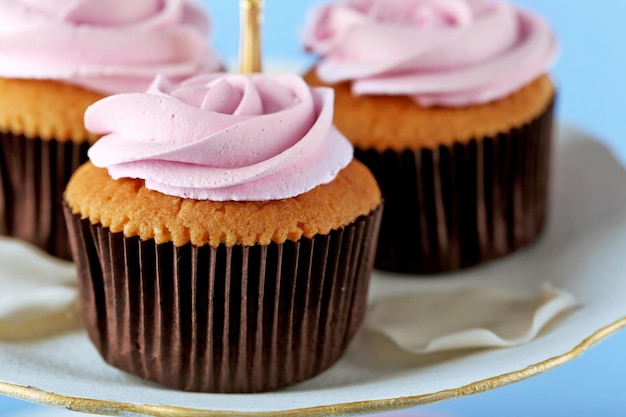 Tasty cupcakes on stand on color background