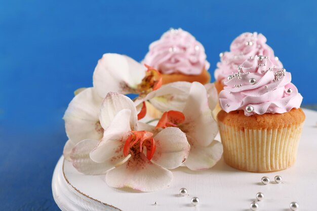 Tasty cupcakes on stand on color wooden background