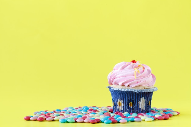 Tasty cupcakes with candles on colorful wall