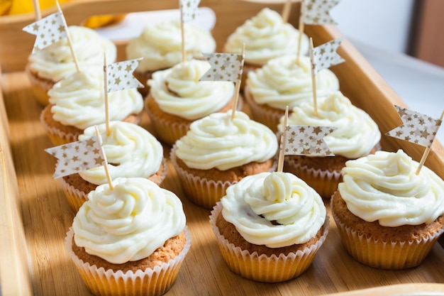 Tasty cupcakes with cream on wooden tray on holiday table with flags