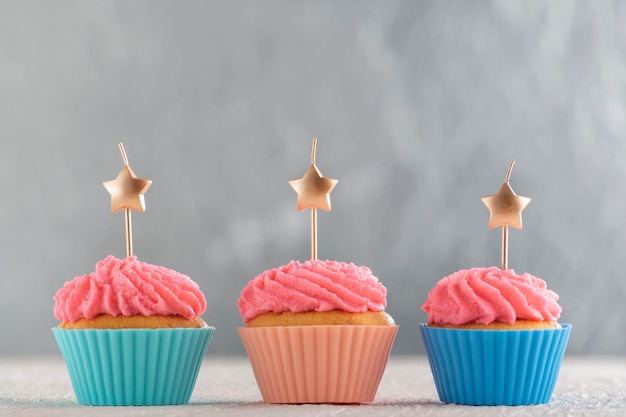 Tasty cupcakes with pink cream icing and candles. Sweet delicious muffins with copy space. Silver background