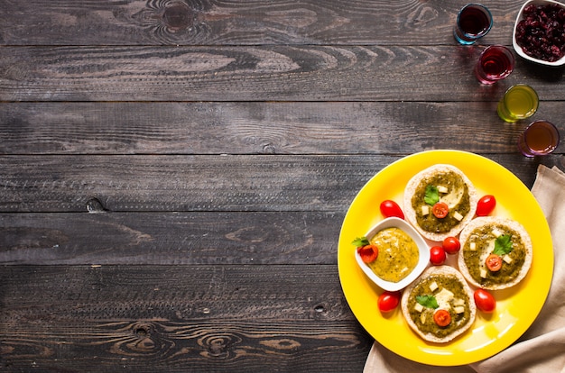 Tasty and delicious bruschetta with avocado, tomatoes, cheese, herbs, chips and liquor on wood