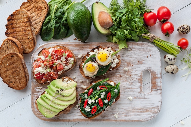 Tasty and delicious bruschetta with tomatoes, spinach, feta avocado red chili pepper and blue cheese. 