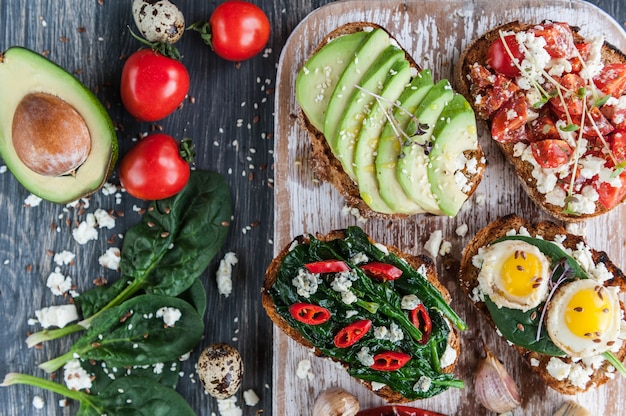 Tasty and delicious bruschetta with tomatoes, spinach, feta avocado red chili pepper and blue cheese. 