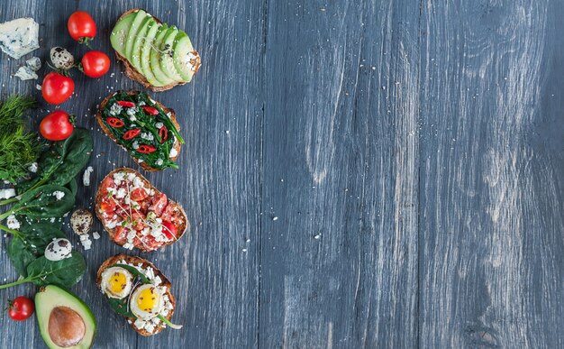 Bruschetta gustosa e deliziosa con pomodori, spinaci, peperoncino rosso di avocado feta e gorgonzola.