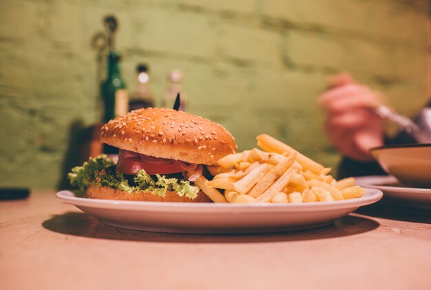 カフェのプレートに美味しいハンバーガー。ジューシーなハンバーガーと一緒にフライドポテト。