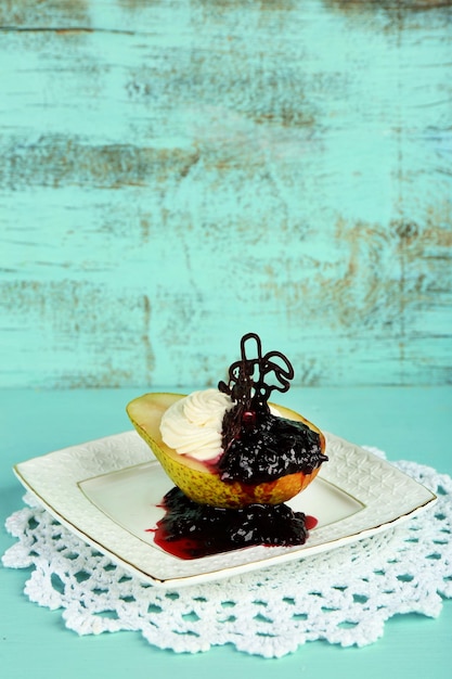 Foto delizioso dessert con crema di pere e salsa di bacche su piatto su sfondo di legno colorato