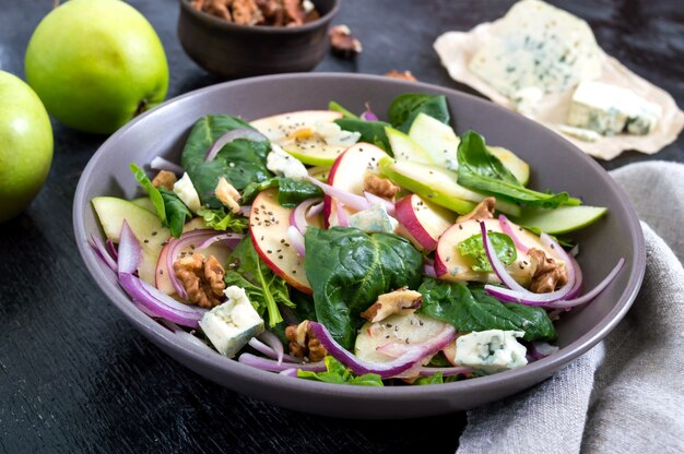 Tasty diet fitness salad with spinach, apples, red onions, blue cheese, nuts