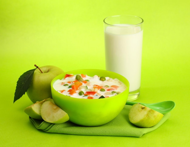 Tasty dieting food and glass of milk on green background