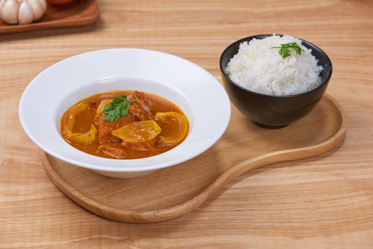Photo 木製の背景にボウルにチキンカレーとおいしいディナー