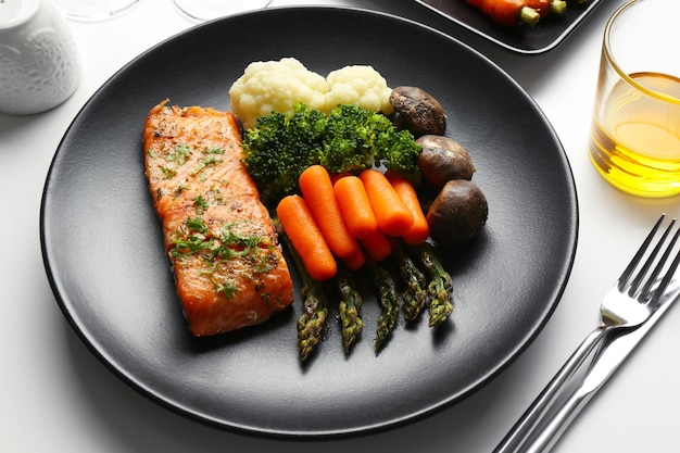 Foto un piatto gustoso con carote e salmone su un piatto nero in primo piano