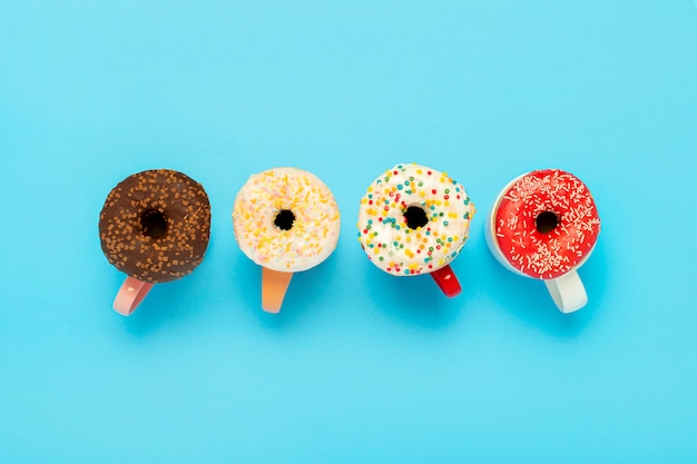 Tasty donuts and cups with hot drinks on a blue surface. Concept of sweets, bakery, pastries, coffee shop. . Flat lay, top view