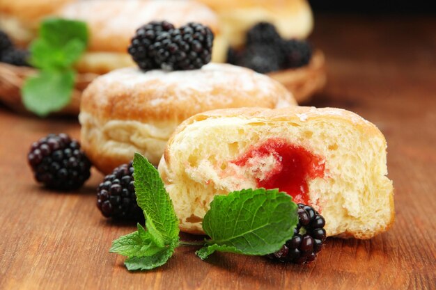 Tasty donuts with berries on wooden table