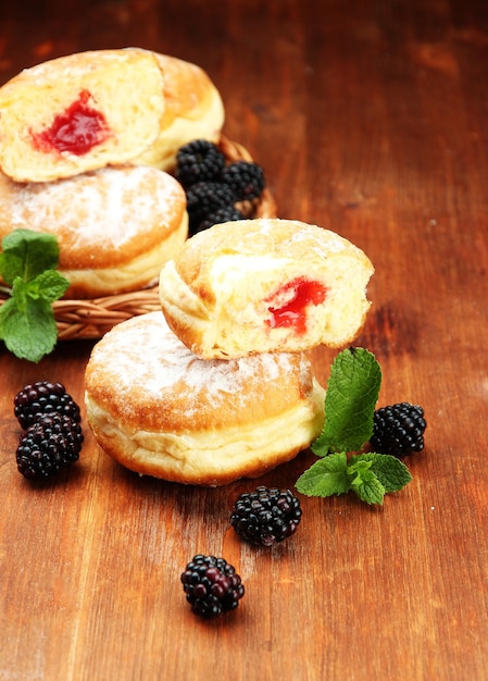 Tasty donuts with berries on wooden table