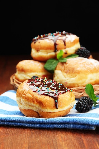 Tasty donuts with chocolate and berries on wooden table