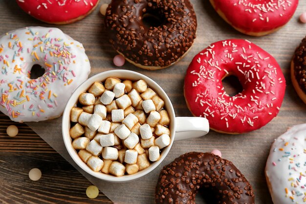 Tasty donuts with cup of coffee on table