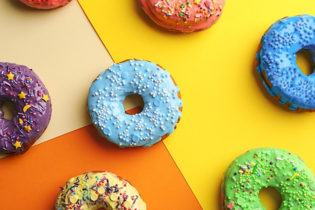 Tasty donuts with sprinkles on color background