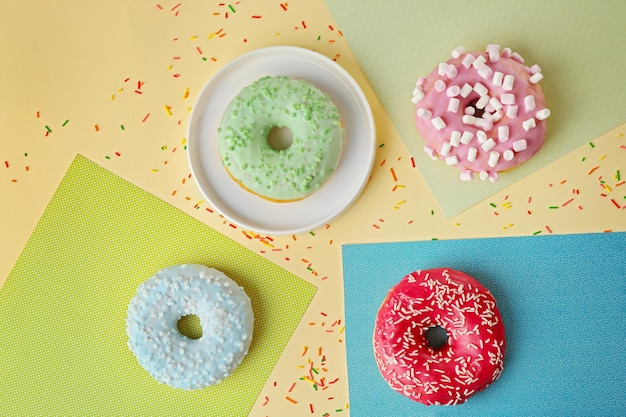 Tasty donuts with sprinkles on colorful background