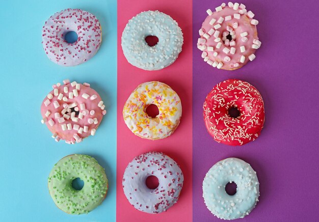 Tasty donuts with sprinkles on colorful background