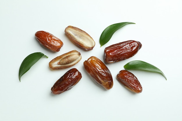 Tasty dried dates with leaves on white