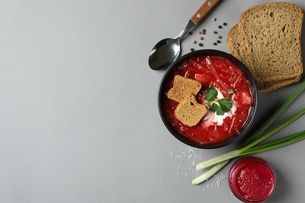 Tasty eating with borscht and ingredients on gray table