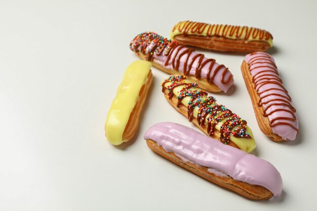 Tasty eclairs with different topping on white background