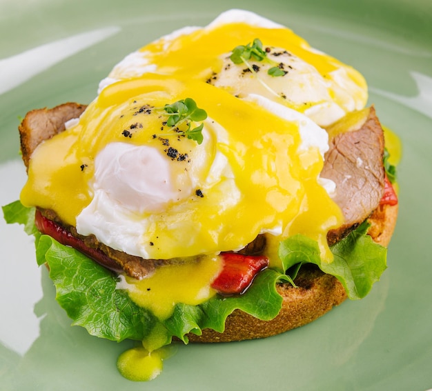 Tasty egg Benedict on green plate