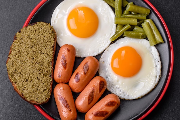 Tasty English breakfast of fried eggs beans asparagus sausages with spices and herbs