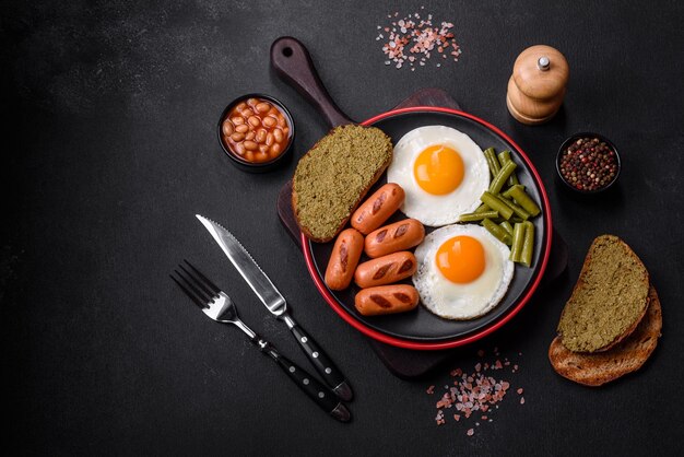 Tasty English breakfast of fried eggs beans asparagus sausages with spices and herbs