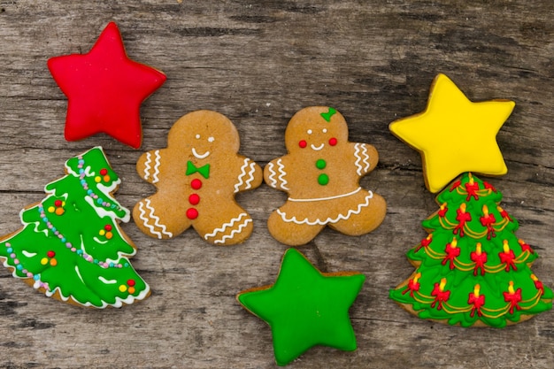 Tasty festive Christmas cookies in the shape of Christmas tree, Gingerbread man and stars on rustic wooden table. Top view