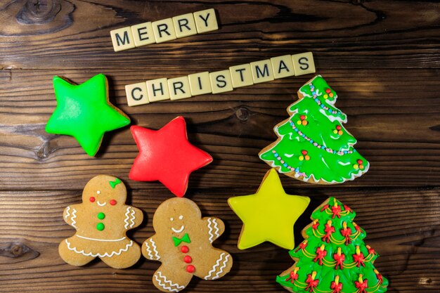 Tasty festive Christmas gingerbread cookies and Merry Christmas inscription on wooden table. Top view