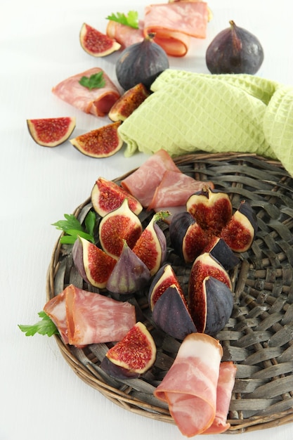 Tasty figs with ham on white wooden table