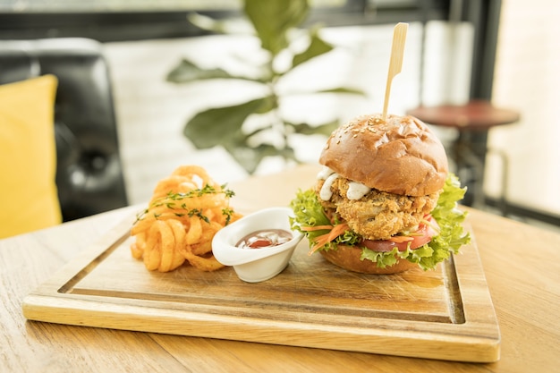 Tasty fired chicken with arugula and mayonnaise sauce served on wooden board, fired chicken Cheese Burger with Spicy Seasoned Curly Fries