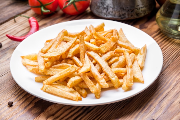 Tasty french fries on cutting board,  wooden table