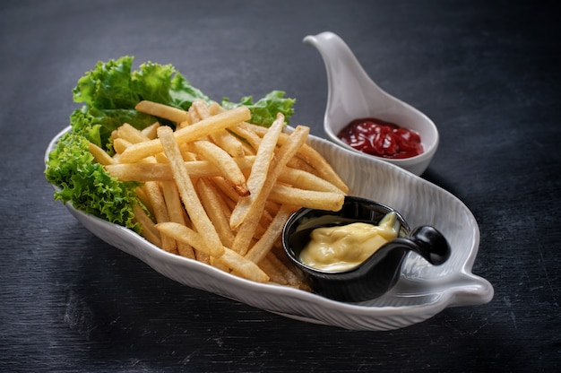 Photo tasty french fries on white plate, on wooden table