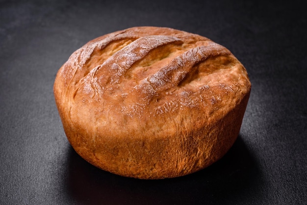 Tasty fresh baked in oven white bread on a dark concrete background