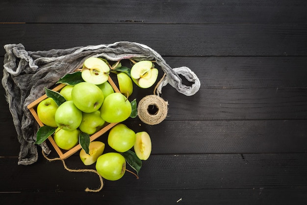 Вкусные и свежие зеленые яблоки в деревянной коробке на черном деревянном фоне. Вид сверху. Копировать пространство