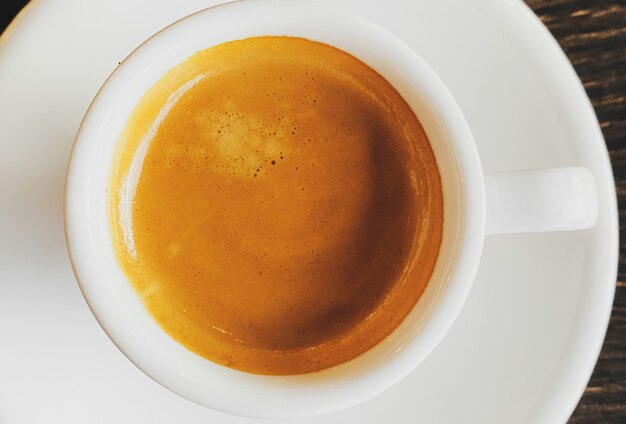 Tasty fresh italian espresso in white ceramic cup on table in cafe