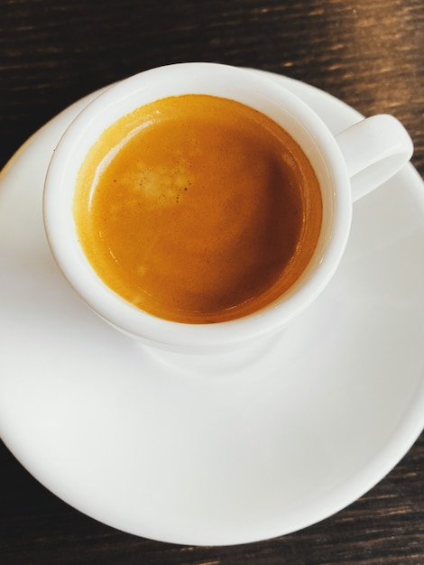 Tasty fresh italian espresso in white ceramic cup on table in cafe