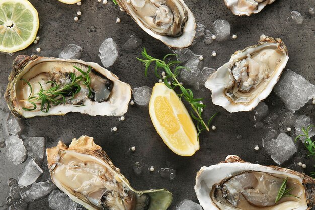 Tasty fresh oysters with sliced juicy lemon and ice on dark background Aphrodisiac food for increasing sexual desire