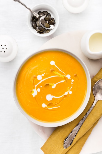 Tasty fresh pumpkin creamy soup with cream on grey marble background. 